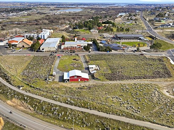 Tight aerial of the 691 Windmill Rd parcel showing the existing red building, surrounding gravel and brush, and the Yakima River basin in the distance behind the Horse Heaven Hills