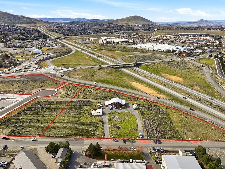 Aerial view of 2.46 acres of C2 commercial land at 691 Windmill Rd, Richland, Washington, with the parcel outlined in red beside the Queensgate freeway interchange and the Horse Heaven Hills on the horizon